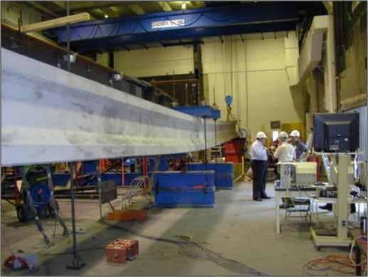 This photo shows a simply supported prestressed concrete bridge girder with a large imposed vertical deflection being tested inside the Federal Highway Administration Turner-Fairbank Highway Research Centerâ€™s Structural Testing Laboratory.