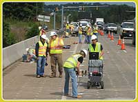 Workers on bridge with cars