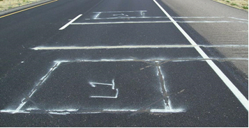 Figure 5. Photo. Double threshold WIM system setup with piezoquartz sensors. This photo shows a double threshold weigh-in-motion (WIM system setup with piezoquartz sensors. There is a roadway that has been marked for the installation of two piezoquartz sensors. Using road paint, two large squares have been painted and labelled "L1" and "L2." A separating line has been painted between the two sensor installation sites.
