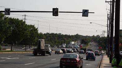 This photo shows vehicles on a roadway passing under the following signage (from left to right): a left/through sign, a changeable light-emitting diode (unlit) right turn only sign, and an ordinary right turn only sign.