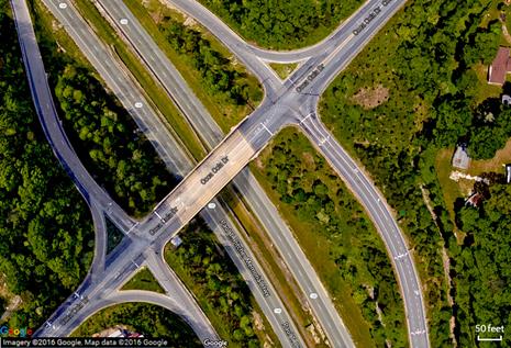 This map provides an aerial view of a signalized diamond interchange at Paul Pitcher Memorial Highway (Route 100) and Coca Cola Drive in Howard County, MD.
