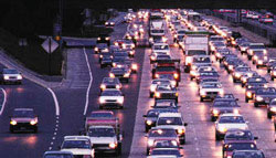 A congested highway at nighttime with traffic entering from onramps, adding to the backup.