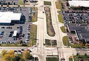 Aerial photograph of an median U-turn intersection in which direct left turns from the major approach have been eliminated. In order to turn left from the major road onto an intersecting cross-street, the driver must first pass the intersection and then make a U-turn at a downstream signalized median opening designed for that 