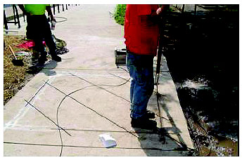 Figure 4-29. Type D loop installation. Technician is pressing loop wire into a 6-foot (1.8-meter) wide palm shaped loop that was sawed into a bike path. The wire pattern has four diagonal cuts traversing the palm to detect the presence of a bicycle as it traverses the configuration. Additional details are given in the text. 