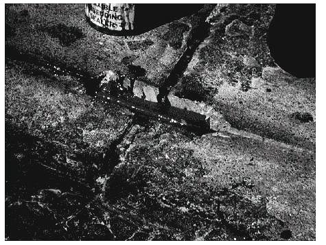Figure 5-15. Crossing pavement joints using rigid tubing. Photograph of wire crossing a pavement joint encased in conduit to prevent damage to the wire.
