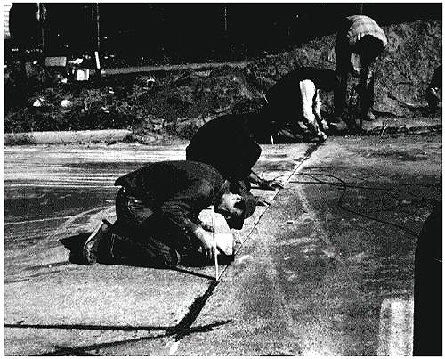 Figure 5-29. Crew applying sealant by hand. Photograph of four-man crew applying sealant by hand. 