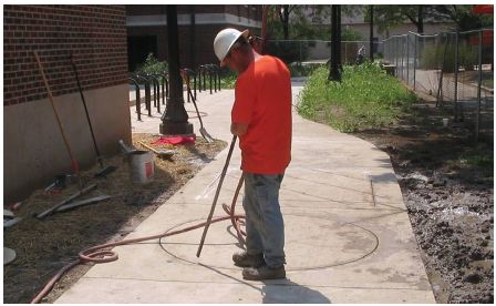 Figure 5-45. Blowing out debris from sawcut. The installation technician uses compressed air guided through a long tube to blow out the small particles and dust that remain in the circle after the saw cut. If these are not removed, the sealant will adhere to them rather then to the edge of the saw cut. It will then pop out during freeze thaw cycles of temperature.