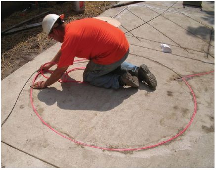 Figure 5-47. Inserting backer rod material over loop wire. After seating the loop wire, the technician kneels down by the sawcut and inserts backer rod by hand which will keep the loop wire from floating to the top when the sealant is installed.