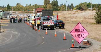 A highway scene with cars and emergency vehicles and a sign that reads "Wreck Ahead"