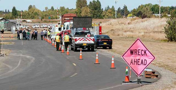 A highway scene with cars and emergency vehicles and a sign that reads 'Wreck Ahead'