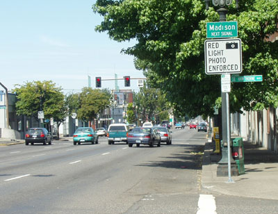 The picture shows a simple advance street name sign that reads "Madison next signal" and warns that the red light is photo enforced. 