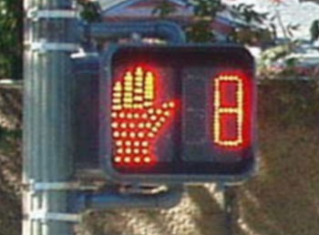 Figure 69. Examples of countdown and animated eyes pedestrian signal displays. Photos. The photo to the left shows a countdown display with a Flashing don't Walk symbol next to a digital number (eight). The digital number counts down second by second and reflects the amount of time remaining during the "flashing don't walk" interval. The photo to the right shows an "animated eyes" display in a fluorescent blue color. The "eyes" are shown directly above the walk symbol and indicate that pedestrians should look out for conflicting movements.
