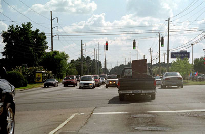 Figure 74. Example of deflection in travel paths for through vehicles. Photo.This photo shows a pickup truck proceeding through an intersection; opposite the vehicle are two lanes of cars waiting to turn left. The pickup driver is required to shift to the right to continue through the intersection, as the alignment of the through lane partially intersects the oncoming traffic.