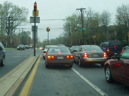 The example shows a narrow left-turn lane at a retrofitted signalized intersection. Vehicles in the left turn lane shy away from the median curb toward the stripe that separates the left-turn lane from the adjacent through lane.