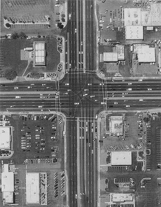 Figure 119. Intersection with turn paths delineated for dual left-turn lanes in Tucson, Arizona (Kolb Road/22nd Street), June 1998. Photo. This aerial view of a large intersection in Tucson, Arizona shows delineated paths for dual left-turn lanes on all approaches. The dual left turn lanes are offset to the left to improve sight distance for protected-permissive operation.