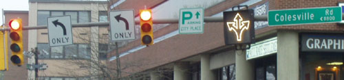Figure 125. Example use of variable lane use sign to add a third left-turn lane during certain times of day. Photos. (A) The top picture shows a fiber optic variable lane use sign that allows through and right-turn movements in the outside lane. (B) At the same intersection during the evening peak period, the sign changes to allow left-turn, through, and right-turn movements.