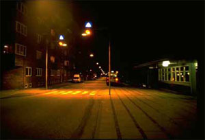 Figure 37. Photo. Adequate lighting can improve pedestrian safety at night. This photo shows a midblock crosswalk on a narrow, two-way road at night, with two streetlights shining down on the crosswalk to illuminate it.
