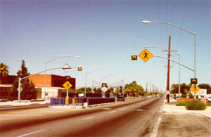 Figure 40 Photo. Fences or railings in the median direct pedestrians to the right and may reduce pedestrian crashes on the second half of the street. The photo shows a four-lane roadway with a refuge island in the middle with rails to guide pedestrians through it.