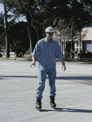 Figure 1: Photo. An inline skater. A man using inline skates is skating in a parking lot.