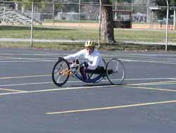 Figure 11: Photo. Hand cycle. A man is using a hand cycle to travel in a parking lot.