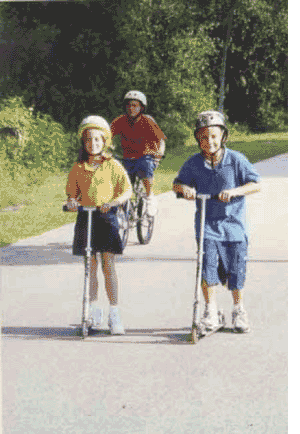 Figure 2: Photo. Nonmotorized kick scooter. A boy and girl are using nonmotorized kick scooters on a trail