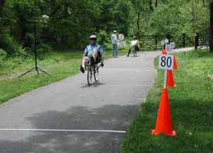 Figure 34: Photo. Participants accelerated along a 60-meter (200-foot) section of the course. A participant on a recumbent bicycle is accelerating to his normal riding speed. This section of the course is marked with transverse lines that are 12.2 meters (40 feet) apart.