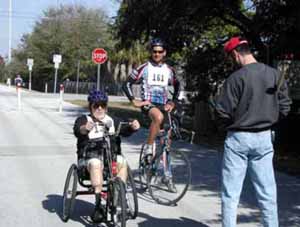 Figure 35: Photo. Participants were asked to accelerate to their normal speed. An event staff person is instructing two participants - one on a bicycle and one on a hand cycle - at the acceleration station.
