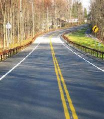 A highway that has signs and guardrails on both sides of the road.