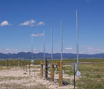 This picture shows numerous poles, each about 3 m (10 ft) apart, with electronic equipment attached. There is also fencing and gates.
