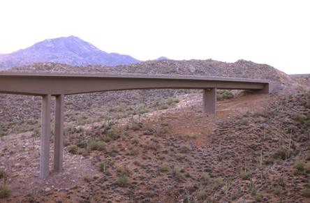 This picture shows one end of a bridge spanning a valley. Even though this is new construction, the majority of the vegetation under the bridge is intact.