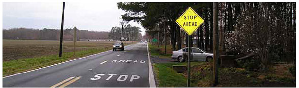 Figure 2. Photo. STOP AHEAD Pavement Marking with Warning Sign. Shows a STOP AHEAD pavement marking used in conjunction with a stop ahead warning sign. The sign is a fluorescent yellow diamond sign.