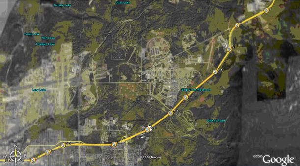 Figure 21.  Photograph.  Proposed pavement marking installation sites.  An aerial photograph taken from GoogleTM Earth shows the proposed pavement marking installation sites along Glenn Highway State Route 1 outside Anchorage, AK.  A yellow line indicating the Glenn Highway begins at the bottom left of the photograph and extends to the top right.  Along the illustrated length of the highway, there are nine proposed installation sites marked by circles at the beginning and end point of each site.  The beginning points for Sites 2 through 8 are the same as the end points of the previously numbered sites.