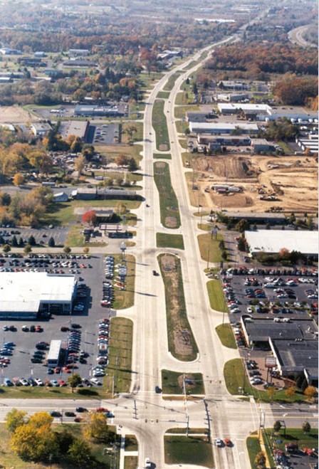 . The photo shows an aerial view of a median U-turn intersection (MUT) treatment corridor in Michigan. The major road runs vertically, and the minor roads intersect the major roads. U-turn facilities are provided at intervals on the corridor.