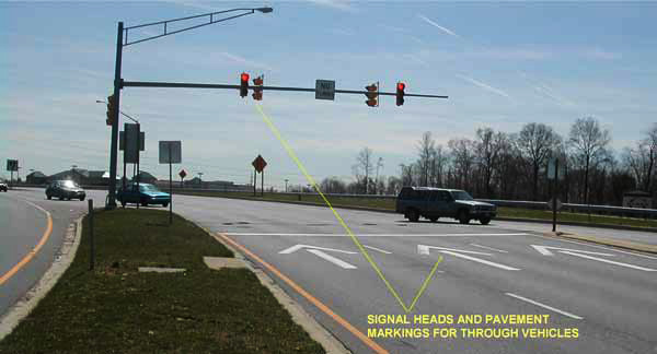 The photo has arrows pointing to signal heads and pavement markings for through vehicles at the intersection of MD 210 and MD 228 in Accokeek, MD.