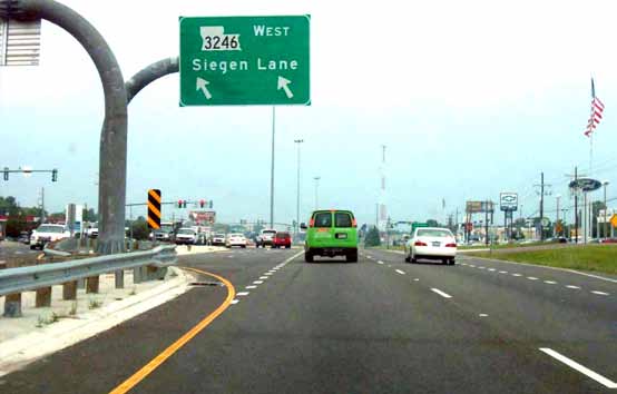 The photo shows a continuous flow intersection overhead sign at a displaced left-turn (DLT) intersection in  Baton Rouge, LA.