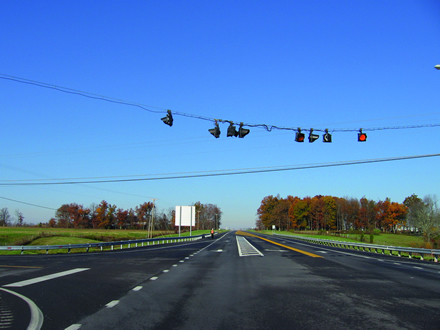 Figure 9. Photo. Cross hatching in median at an intersection with left-turn bay. The figure shows an intersection from the left side of the road. There is a yellow median separating the two directions of travel. There is white hatching for the oncoming traffic that provides drivers with a left-turn bay.