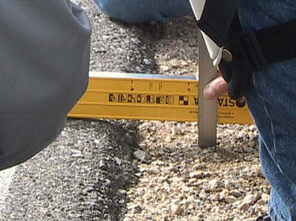 This photograph shows the use of a straight edge and a ruler to implement the measurement of pavement edge drop-off height.