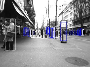 This photo shows true detections and typical false positives. People are tracked in an urban environment on sidewalks using white bounding boxes. Blue bounding boxes outline trees and objects.