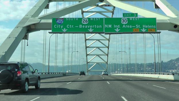 This photo shows the driving image for scenario 1 critical point 1. There is a four-lane single direction bridge deck with vehicles traveling on it. The sign above the left-land lane is labeled  City Ctr  with a down arrow. The next lane has a sign labeled  Beaverton  with a down arrow. The third lane has a sign labeled  NW Ind. Area  with a down arrow, and the right-hand lane has a sign labeled  St. Helens  with a down arrow. Above the two right-most lanes, there is also a sign labeled  Exit 3. 