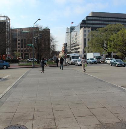 Illustration of what a pedestrian might see as he or she attempts to cross from the north side of New York Avenue Northwest to the south side of the street along 7th Street Northwest. The traffic traveling northbound (closest to the crosswalk) is waiting for the pedestrians to clear before completing a right turn. The photo is taken from the perspective of the pedestrian.