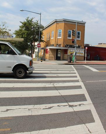 Illustration of what a pedestrian might see as he or she attempts to cross from the east side of Georgia Avenue Northwest to the west side of the street along Irving Street Northwest. The photo is taken from the pedestrian perspective. Cross traffic has the right of way, and a van is beginning to enter the crosswalk.