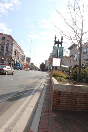 View of the planters located between the southbound lanes of traffic and the adjacent sidewalk along Wisconsin Avenue. The planters are heavy brick structures with planted trees and shrubbery.