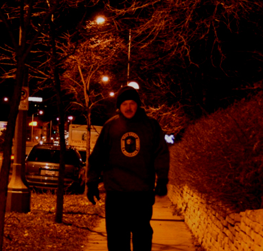 Figure 7. Photo. Facial recognition under high lighting. This image features the same road and pedestrian as figure 6. Overhead luminaires are illuminated, there is higher lighting, and the man’s face is recognizable.