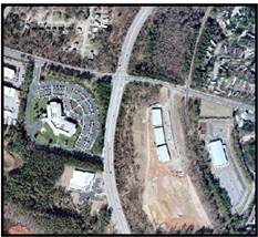 Figure 12-D. Photo. Photo of median type. The aerial view that corresponds to subfigure C shows that the grass median changes to mountable pavement as the road approaches an intersection, then back to grass on the other side of the intersection.