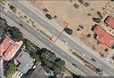 Figure 13. Screen shot. Verifying data with aerial imagery. A close-up aerial image from Google® Earth™ shows one study corridor, which is a four-lane divided roadway with raised median. A red arrow line indicates the position from which a video still image, shown in figure 14, was captured.