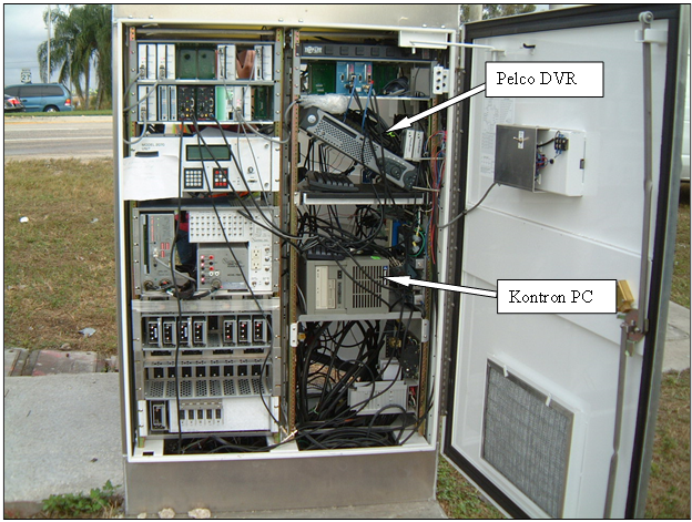 Figure 3. Photo. Naztec cabinet in Florida with D-CS monitoring equipment. The photo shows the inside of a Naztec cabinet with detection-control system monitoring equipment. The monitoring equipment includes a Pelcoâ„¢ digital video recorder and Kontronâ„¢ personal computer, which are labeled.