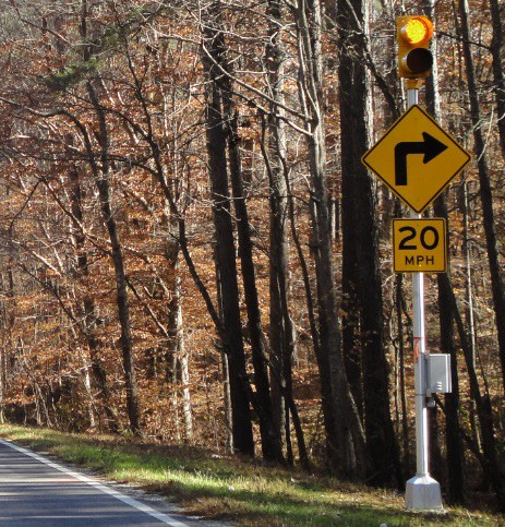 Figure 169. Photo. Flashers to existing curve warning sign. This figure shows an example of flashers added to an existing curve warning sign. Flashing amber lights are added to an existing curve warning sign.