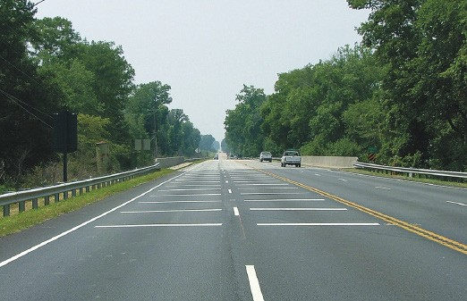 Figure 149. Photo. Transverse markings. This figure shows an example of transverse markings. Transverse markings are a series of white transverse barsâ€•either flat or raisedâ€•placed across the center of the lane and spaced progressively closer together to create the illusion that driver speed is increasing.