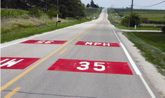 Figure155. Photo. Enhanced speed limit legend with colored surfacing. This figure shows an example of an enhanced speed limit legend with colored surfacing. An enhanced speed limit legend with colored surfacing involves the same treatment as the speed limit pavement legend, except the legend is surrounded by an additional colored box. The legends are spaced at regular intervals to remind drivers of the speed limit. The colored outline is not Manual on Uniform Traffic Control Devices compliant and requires Federal Highway Administration experimental permission.