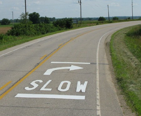 Figure 156. Photo. SLOW pavement legend. This figure shows an example of a SLOW pavement legend. A pavement marking legend is installed in the travel lane to indicate SLOWâ€”the driver should reduce speed.